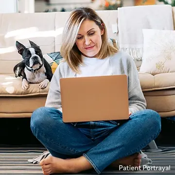 Patient portrayal of a woman sitting on the floor with her laptop