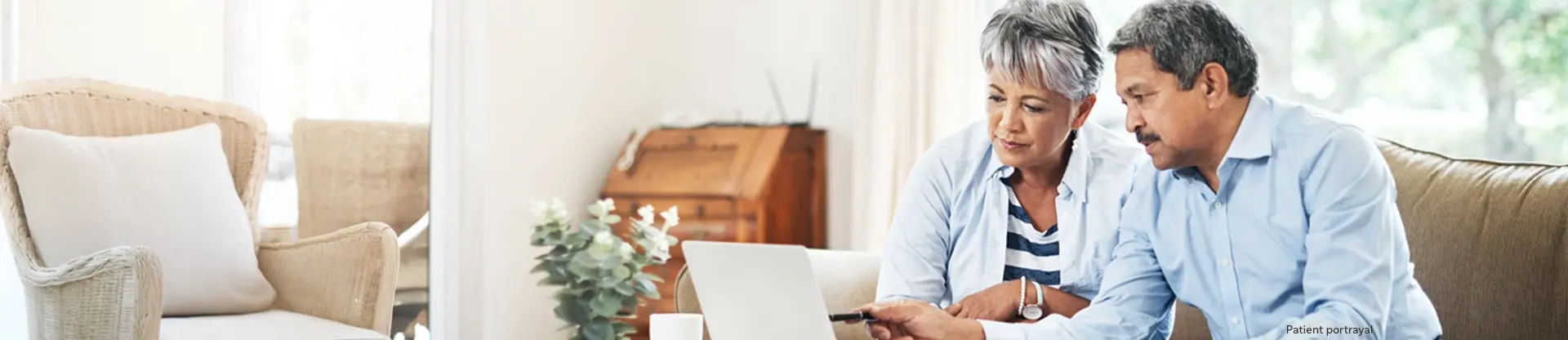 Patient portrayal of a man and woman sitting on a sofa looking at a laptop computer